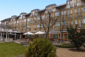 ein großes Gebäude mit Tischen und Sonnenschirmen davor in der Unterkunft Best Western Hotel Braunschweig Seminarius in Braunschweig