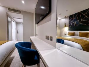 a hotel room with two beds and a desk and chairs at NOX Edgware Road in London