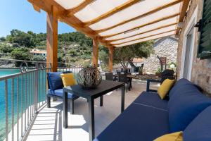 eine Terrasse mit einem blauen Sofa und einem Tisch in der Unterkunft Seaside Cottage Maslina in Gdinj