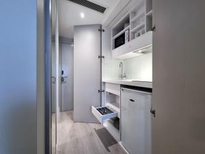 a small kitchen with white cabinets and a refrigerator at NOX Edgware Road in London