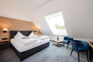 ein Schlafzimmer mit einem Bett und einem blauen Stuhl in der Unterkunft Landhotel Freitag in Sankt Paul im Lavanttal