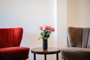 un jarrón de flores sentado en una mesa junto a dos sillas en Landhotel Freitag, en Sankt Paul im Lavanttal