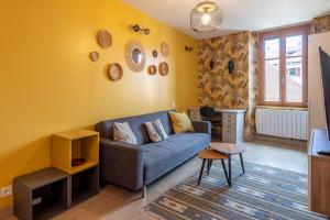 a living room with a blue couch and a yellow wall at Reflet des Alpes Furnished flat in Annecy