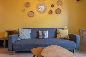 a blue couch in a living room with a yellow wall at Reflet des Alpes Furnished flat in Annecy