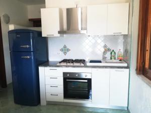 uma cozinha com armários brancos e um frigorífico azul em Luna blu em Erchie