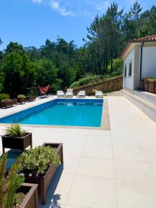 una piscina en un patio trasero con sillas y árboles en Casa Valfonte - Moradia com piscina 