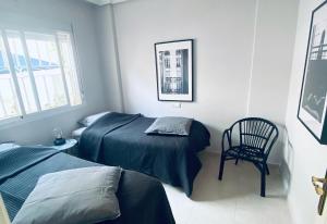 a bedroom with two beds and a chair at Fresh apartment, 2 bedroom, 2 bathroom, 2 lovely poolareas in Los Alcázares +18 photos