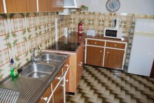 uma pequena cozinha com um lavatório e um frigorífico em Apartamentos Mota na Nazaré