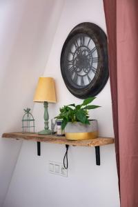 a clock hanging on a wall with a plant on a shelf at Kamienica Stare Miasto- Św . Ducha. in Elblag