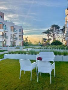 zwei weiße Stühle und ein Tisch im Gras in der Unterkunft Apartament MORZA SZUM Gąski in Gąski