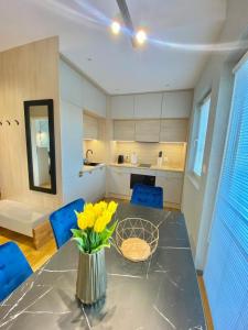 eine Küche mit einem Tisch mit gelben Blumen in einer Vase in der Unterkunft Apartament MORZA SZUM Gąski in Gąski