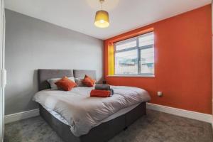 a bedroom with a bed with an orange wall at PRIMEEE LOCATION - Modern Central Apartment in Bristol