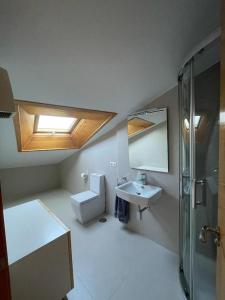 uma casa de banho com um WC, um lavatório e uma clarabóia em Ático en Cambados em Cambados