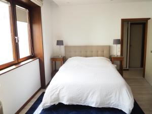 a bedroom with a white bed with two tables and a window at La suite de l'Observatoire in Strasbourg