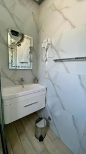 a white bathroom with a sink and a mirror at Hotel Universi in Kolgecaj