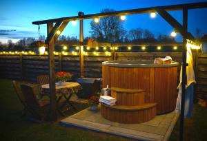 a hot tub in a backyard with lights and a table at Kõrtsitoa Puhkemaja in Unukse