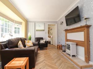 a living room with a leather couch and a tv at The Mews Cottage in Lytham St Annes