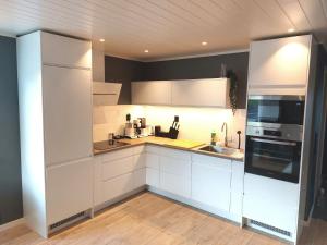 a kitchen with white cabinets and a sink at Lofotlove Apartments - Modern and Comfy Apartments Close To Nature in Sørvågen