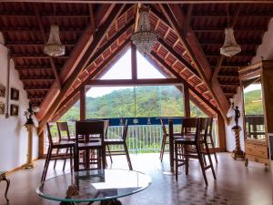 a room with a glass table and chairs and a large window at Antiquus ApartHotel in Guaramiranga