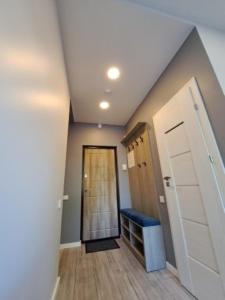 um quarto no sótão com um corredor com uma porta e um banco em Molino Apartamentai em Palanga