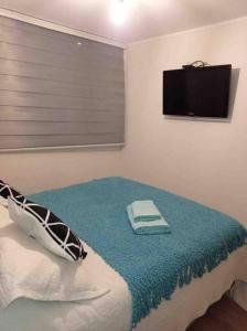 1 dormitorio con 1 cama y TV en la pared en Depto full equipado con estacionamiento y piscina, en Temuco