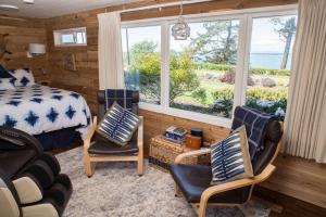 1 dormitorio con 1 cama, 2 sillas y ventana en Dungeness Bay Cottages en Sequim