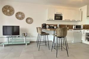 cocina con 2 taburetes y TV en T2 neuf avec belle terrasse proche plage, en Folelli