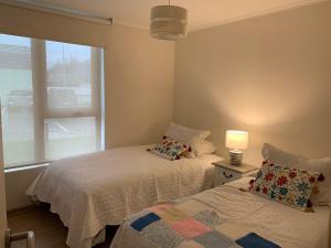 a bedroom with two beds and a lamp and a window at Bienvenidos a Valdivia in Valdivia