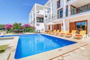 a swimming pool in front of a house with chairs at Villa Cala Nit by Villa Plus in Cala D'or