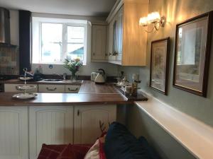 uma cozinha com armários brancos e uma bancada em Wren Cottage em Carmarthen