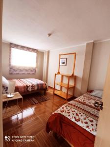 Habitación de hotel con 2 camas y ventana en Departamentos Bellavista La Alborada Huaraz en Huaraz