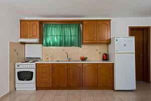 a kitchen with wooden cabinets and a white refrigerator at Residence Vista Del Mare in Acharavi