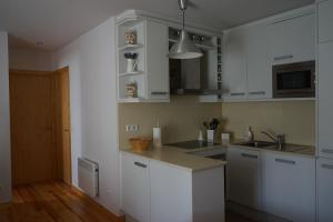 kuchnia z białymi szafkami i zlewem w obiekcie Apartamento con jardín en la Cerdanya w mieście Err