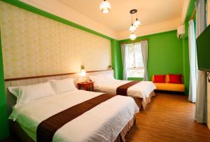 duas camas em um quarto com paredes verdes em 輕旅小站 Soft Travel Hostel em Taitung City