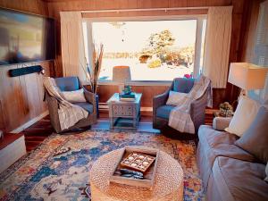 a living room with a couch and chairs and a window at Dungeness Bay Cottages in Sequim