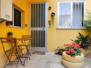 a yellow house with a table and chairs and flowers at Appartamento "C'era una volta" - Ancona in Ancona