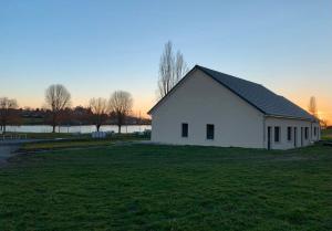 ein weißes Haus auf einem Grasfeld mit einem See in der Unterkunft Résidence du Lac - Proximité Le PAL in Bourbon-Lancy