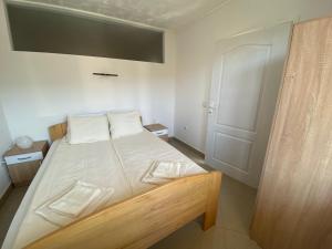 um quarto com uma cama com lençóis brancos e uma porta em Apartmani Bambi Sokobanja em Sokobanja