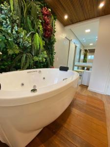 bañera blanca en una habitación con plantas en Pousada Dom Alfredo José, en Campos do Jordão