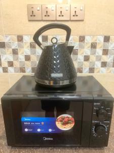 a tea kettle sitting on top of a microwave at Private Bathroom in King Room Bukit Mertajam Alma Impian in Bukit Mertajam