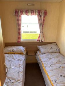 two beds in a small room with a window at Evans Whitehouse Caravan Towyn in Abergele