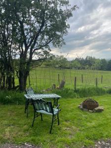 a picnic table and two chairs next to a fire pit at Rhodes To Serenity - Waterfall Shepherds Hut in Cauldon