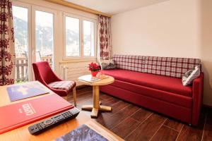 a living room with a red couch and a table at Hotel Caprice - Grindelwald in Grindelwald
