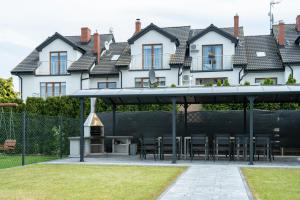 a pavilion with chairs and a grill in front of a house at Villa Luka in Łeba