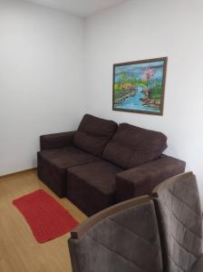 a living room with a brown couch and a painting at AP confortável para sua família in Palmas