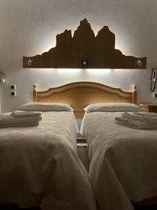 2 letti posti uno accanto all'altro in una camera da letto di Hotel Dolomiti Des Alpes a Misurina