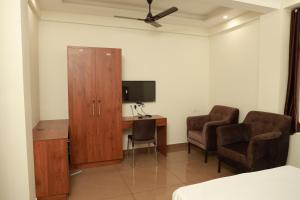 a room with a desk and a cabinet and two chairs at Grace Apart Hotel @Kochi in Cochin