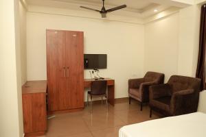 a room with a desk and two chairs and a television at Grace Apart Hotel @Kochi in Cochin