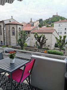 um pátio com uma mesa e cadeiras numa varanda em Velay cocon appartement 4 chambres avec vue sur les monuments em Le Puy-en-Velay