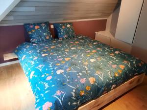 a bed with a blue comforter with flowers on it at Superbe Appart' Bois De Fagne in Malmedy